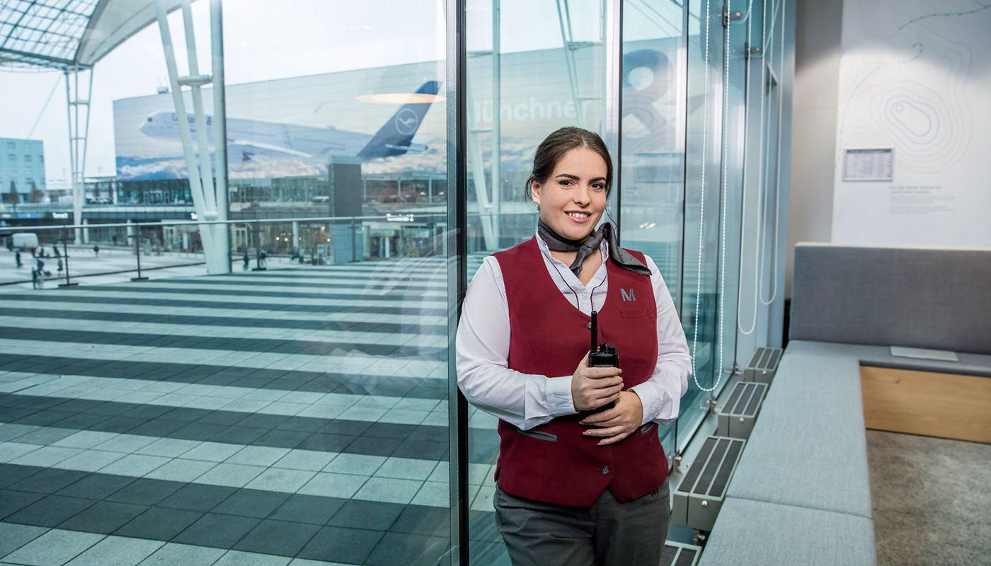 Airport terminal staff holding a radio in front of a window at the airport