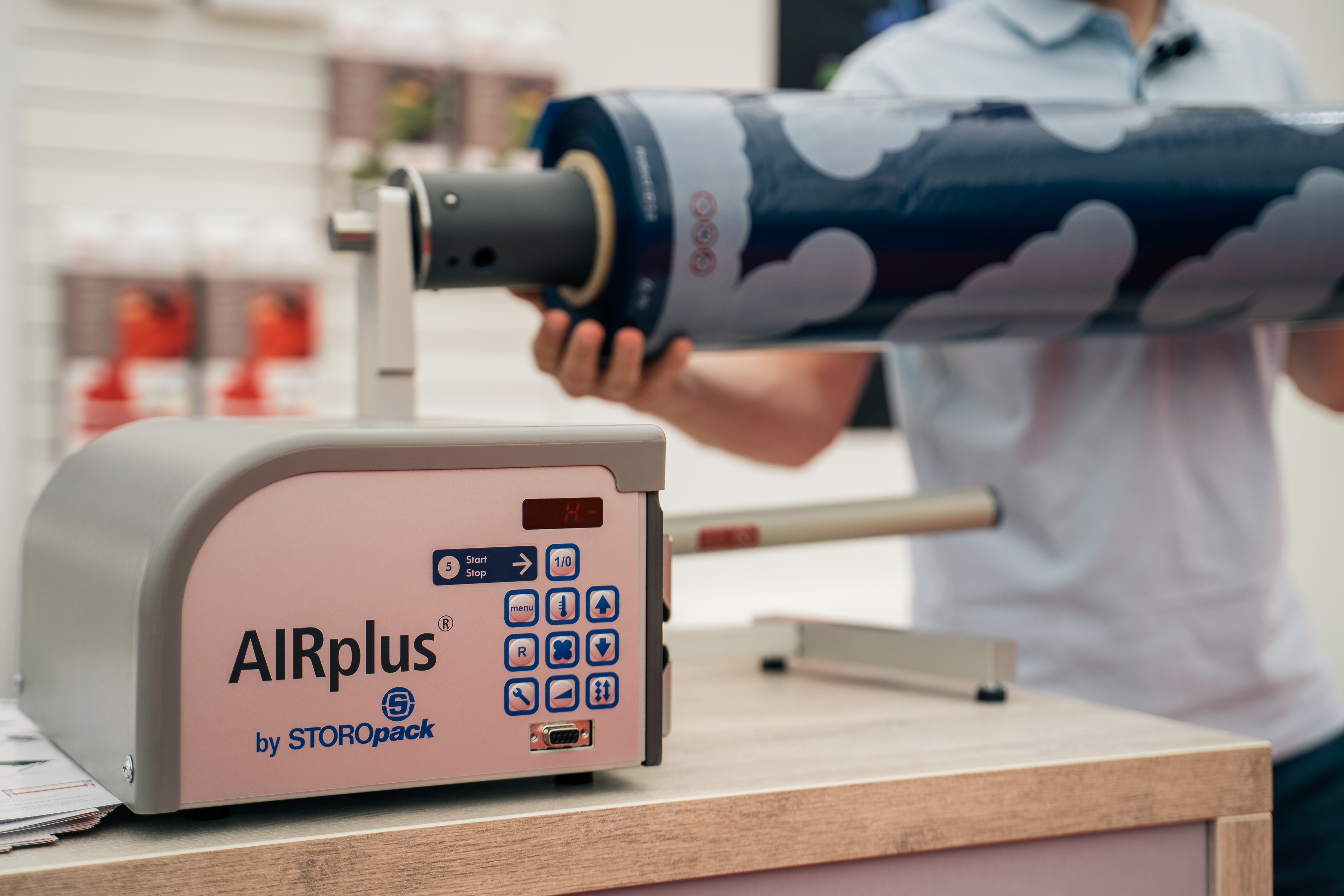 AIRplus Inflator from Soku on a counter with a person holding a Minute Mattress cartridge in the background