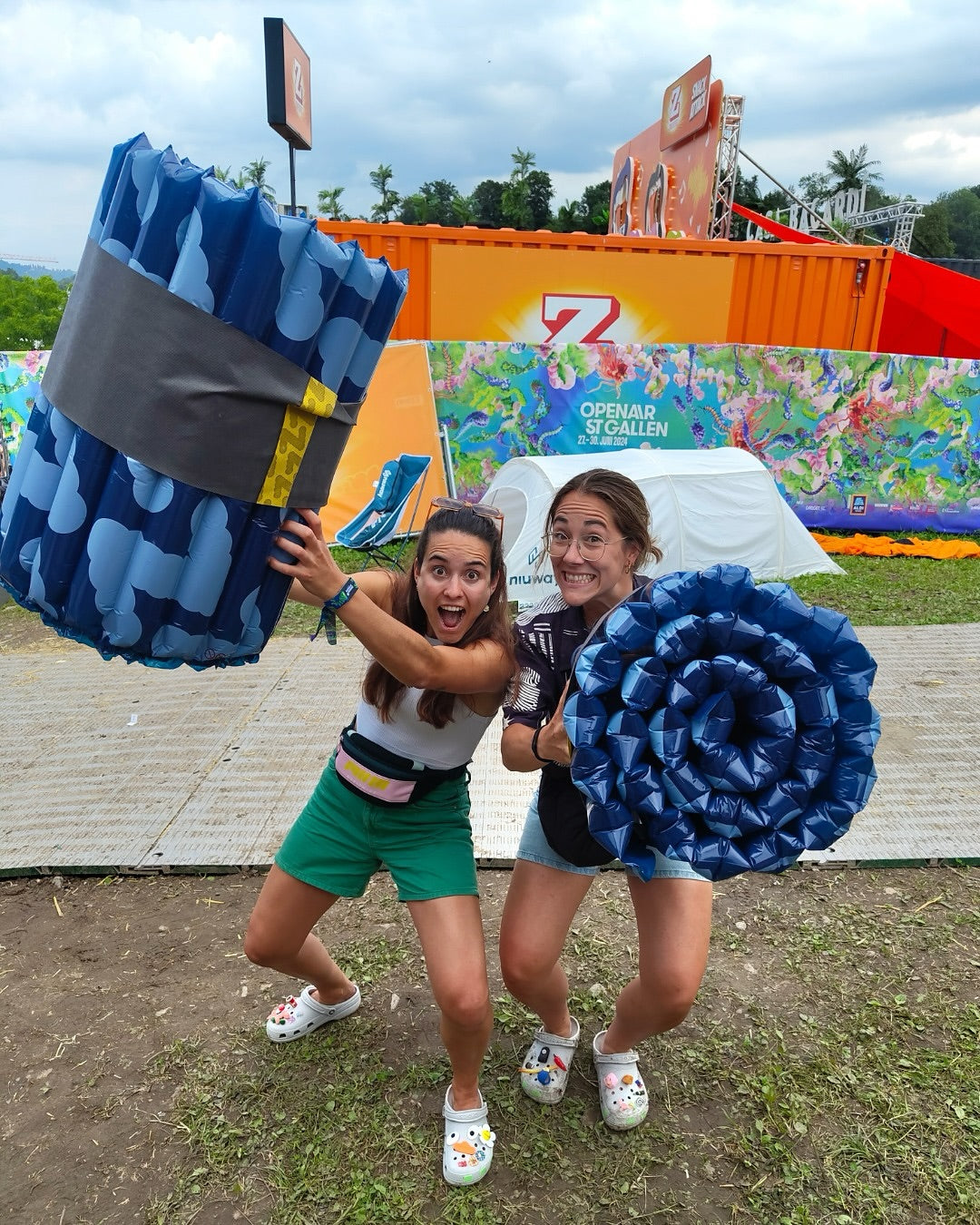 Two happy people holding the Soku Minute Mattress at a music festival.