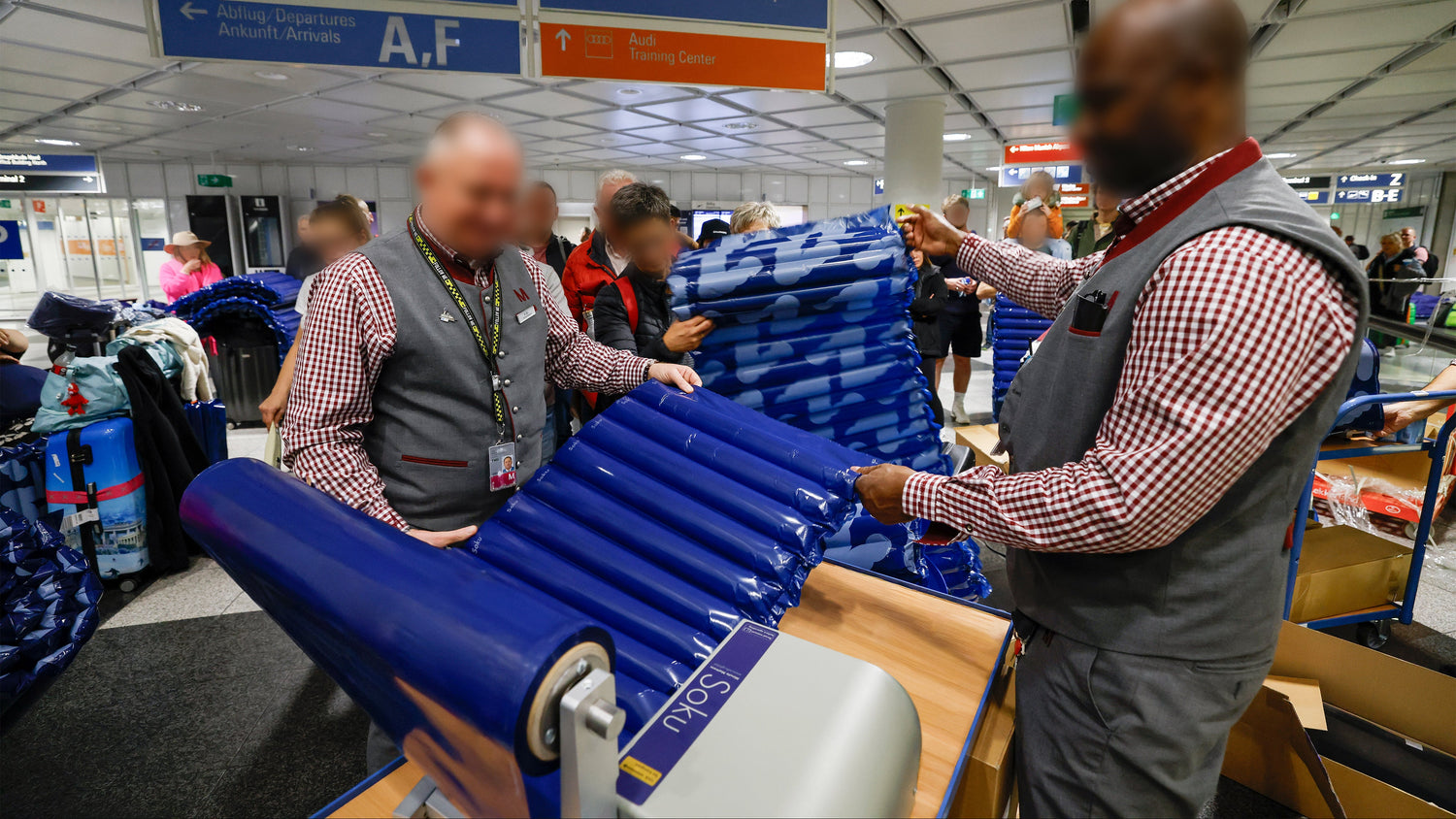 Terminal staff inflating and handing out Soku Minute Mattress at Munich Airport